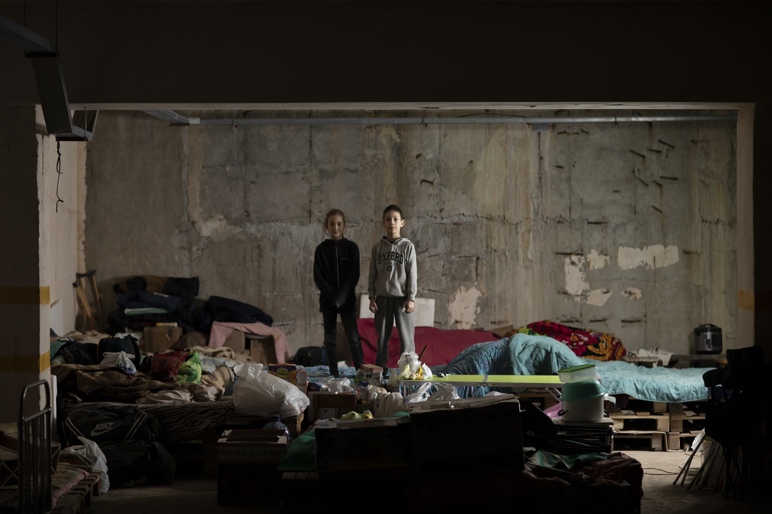 Alina and Artem stand side by side in an underground car park that is serving as a bomb shelter.