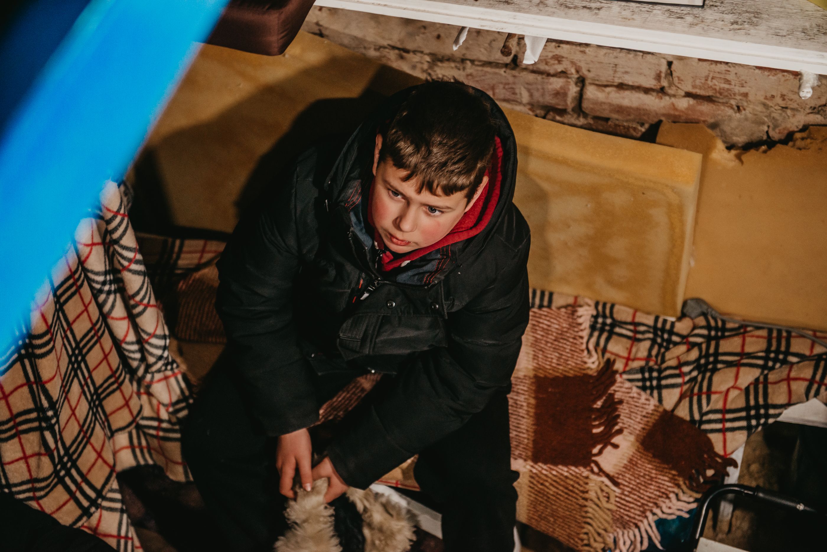 Stepan sits on some blankets in his family's basement.