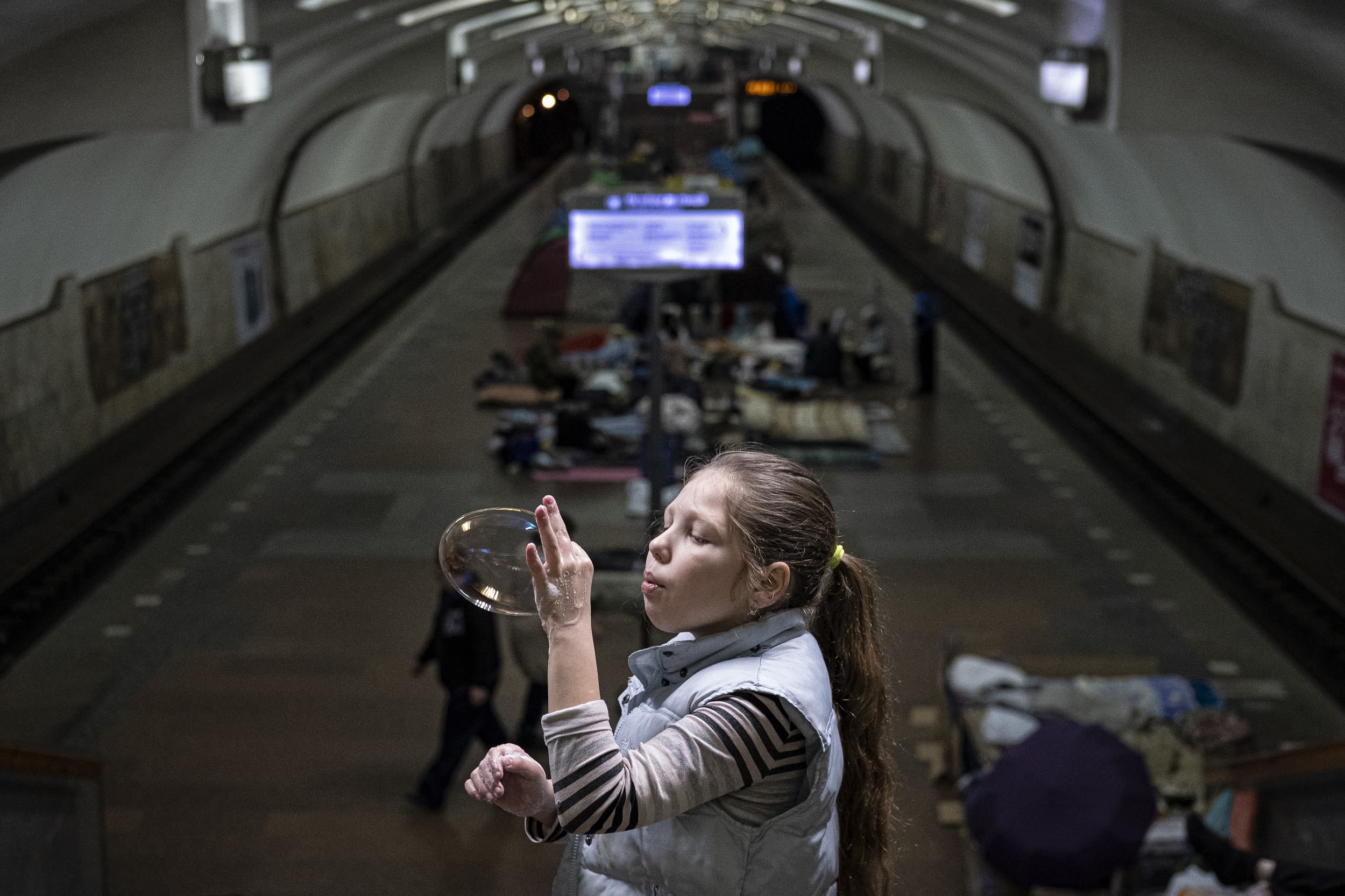 A girl blows a bubble as she stands at a metro station in Kharkiv.